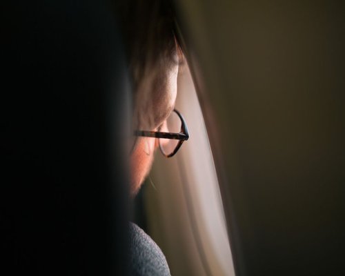 Person resting their eyes while looking out the window